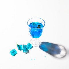 Cold blue tea with ice cubes. Butterfly pea flower  drink on white background with beautiful shadow .Copy space