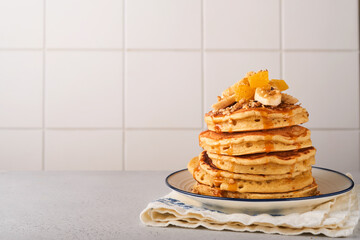 Pancakes. Homemade fluffy pancake with banana, walnut and caramel for breakfast on light concrete background. Delicious pancakes for traditional American breakfast. Selective focus. Mock up.