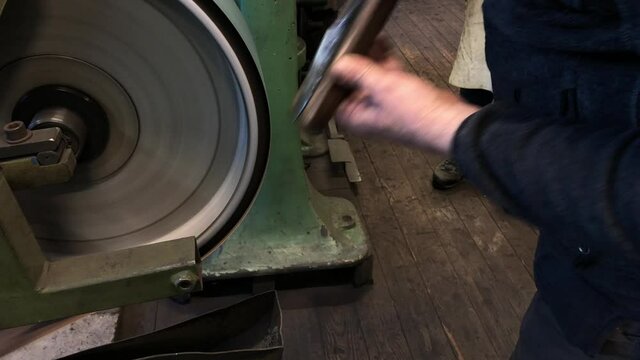Blacksmith sharpening the knife on grinding stone