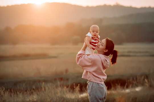 Portrait of a smiling woman standing in a field holding her baby boy, Sakon Nakhon, Isan, Thailand