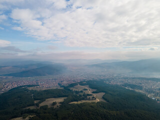 Aerial view of clouds over the city between green mountains