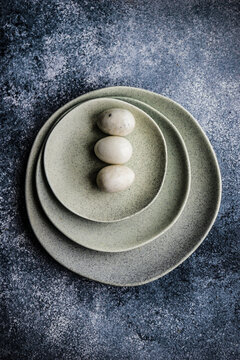 Overhead view of three Easter eggs on a stack of ceramic plates
