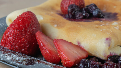 Classic american pancake with berry on black plate background. Crepe with blueberry and strawberry.