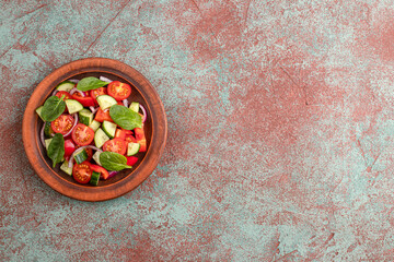 vegetable salad of tomatoes, spinach, onion, sweet pepper, cucumber on a concrete background