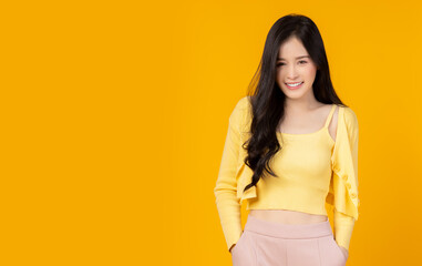 Portrait young asian woman with smile Beautiful girl standing over yellow background and copy space Studio shot Pretty asia female hand in trouser pocket Beauty lady has long hair Attractive girl