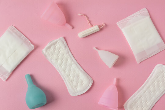 Different types of feminine menstrual hygiene materials products such as pads cloths tampons and cups. Pink background. Menstruation and feminine hygiene concept.