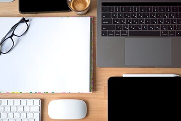 Close up of working place in an office with wooden table and laptop laying, Place of work. a comfortable working place with laptop espresso smartphone notepad paper pen eyeglasses mouse laying on it