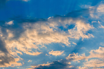 Dramatic sky with feather clouds. Sun's rays shine through clouds. Colorful background.