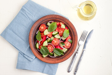 Vegetable salad with tomatoes, sweet peppers, spinach, red onion, cucumber on a white concrete background