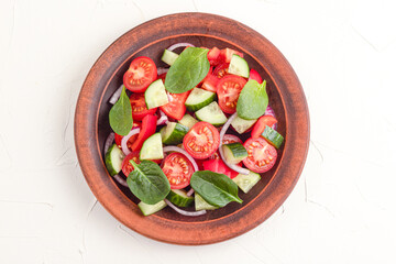 Vegetable salad with tomatoes, sweet peppers, spinach, red onion, cucumber on a white concrete background