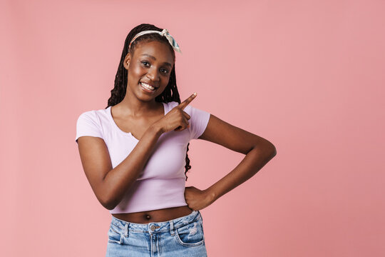 Black young woman with pigtails smiling and pointing finger aside