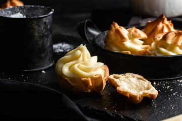 Profiteroles with custard on a dark table. Eclairs