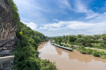 Fototapeta premium The railway at the foot of the mountain, next to the river and blue sky : Tham Krasae, Kanchanaburi Province landmark of Thailand location