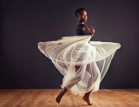 Poetry in motion. Young female contemporary dancer using a soft white white skirt for dramatic effect.