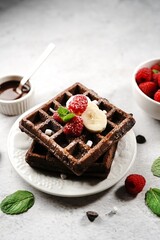 Chocolate square waffles topped with berries and banana, selective focus