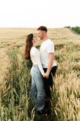 Naklejka na ściany i meble lovers in a wheat field play and laugh. romantic relationship of a modern couple. lovers walk in nature.