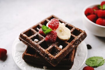 Chocolate square waffles topped with berries and banana, selective focus