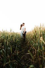 Naklejka na ściany i meble young guy with a girl are walking on a beautiful sunset of the day. couple in wheat field