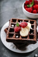 Chocolate square waffles topped with berries and banana, selective focus
