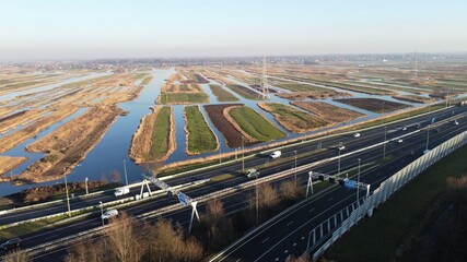 Highway photographed from the air with a drone. Along the Dutch city of Zaandam in the Netherlands with a polder landscape in the background. Choose destination and arrive at your goal. - obrazy, fototapety, plakaty