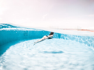 Naklejka premium Woman in a swimming pool, sunset.