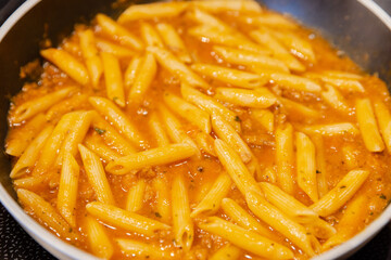penne pasta with bolognese sauce in a pan