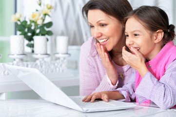 Portrait of happy mother and daughter using laptop together