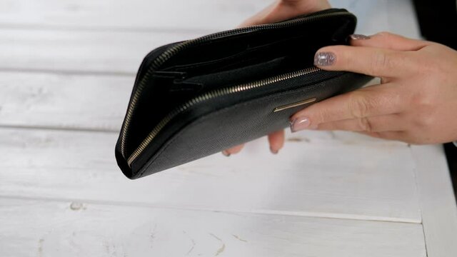 Hand of a woman with an empty wallet and two American dollars close-up. Concept of poverty, economic crisis.