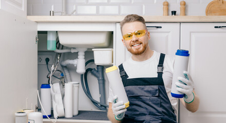 Plumber working install new cartridge for cold water filter in white kitchen