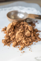 metal spoon with cacao powder close up in white background