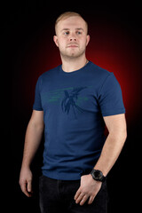 Blond guy in a blue T-shirt on a black illuminated background.