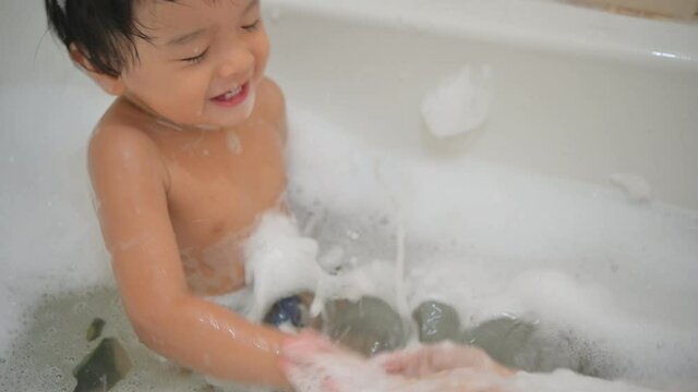 A Baby boy bathes in a bath with foam and soap bubbles