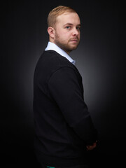 vertical portrait  blond man on a dark background, in a jacket