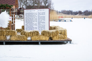 a white angel girl stands by a huge book with holy scriptures, there is a lake in winter