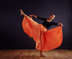 Free form dancing. Female contemporary dancer in a dramatic pose against dark background.