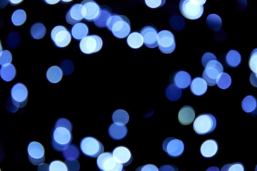 Defocused bokeh christmas cold blue lights on black background. Blue bokeh glitter wallpaper for...