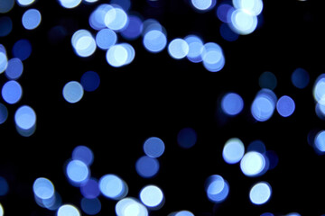 Defocused bokeh christmas blue lights on black background. Blue bokeh glitter wallpaper for...