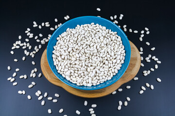 Small white beans on the green plate and wooden board. White beans top view