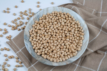 Raw chickpeas on the plate and towel top view.
