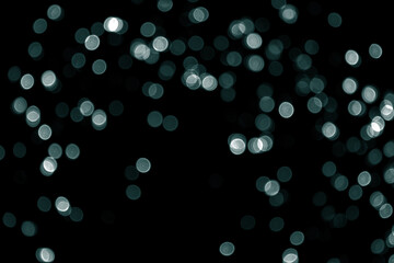 Defocused bokeh christmas little green lights on black background. Blurred abstract green glitter...