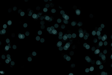 Defocused bokeh christmas small green lights on black background. Blurred abstract green glitter...