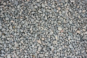 Small stone texture or gravel for background or design. Dark grey closeup small rocks. Real grunge texture background. Grey pebbles stone texture seamless texture. Top view of ground gravel road.