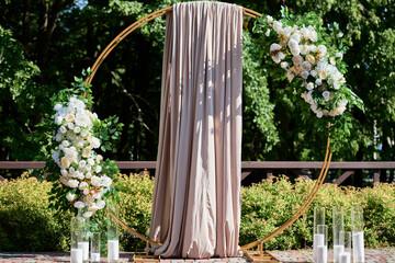 Circle wedding arch decorated with white, pink flowers and greenery outdoors, copy space. Wedding setting on back yard. Floral composition