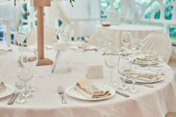 Table setting with sparkling wineglasses, plate with beige napkin and cutlery on table, copy space. Place set at wedding reception. Table served for wedding banquet in restaurant