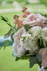 Close up of bridal bouquet of pink and white peony roses and greenery outdoors, copy space. Wedding concept