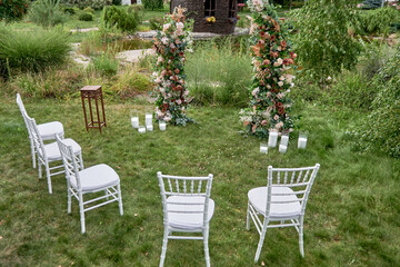 Place for wedding ceremony in garden outdoors, copy space. Wedding arch decorated with flowers. Wedding setting