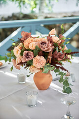 Beautiful floral arrangement of rose flowers and greenery on wedding table in restaurant, copy space. Luxury wedding decorations. Table setting