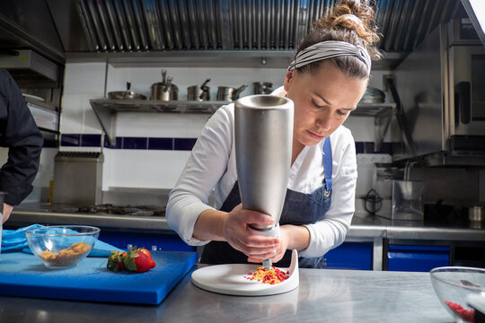 Female cook decorating dessert with whipped cream