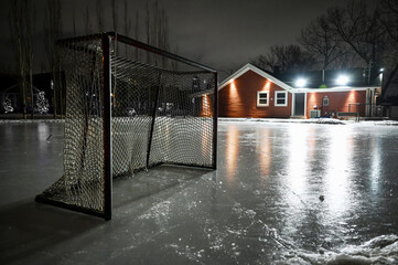 Hockey net on empty outdoor skating rink at night with empty space