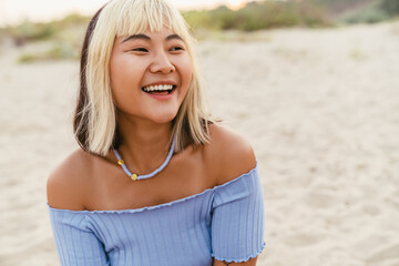 Young asian woman laughing while resting on beach